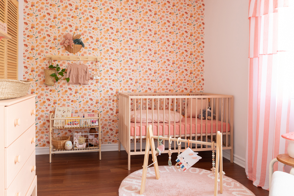 pink nursery with floral wallpaper and wood crib