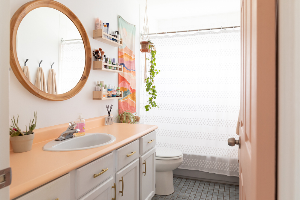 white bathroom with peach counter and gold hardware on vanity
