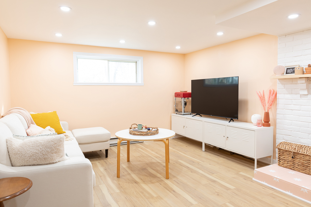 cozy TV area in pink basement with white couch and large TV