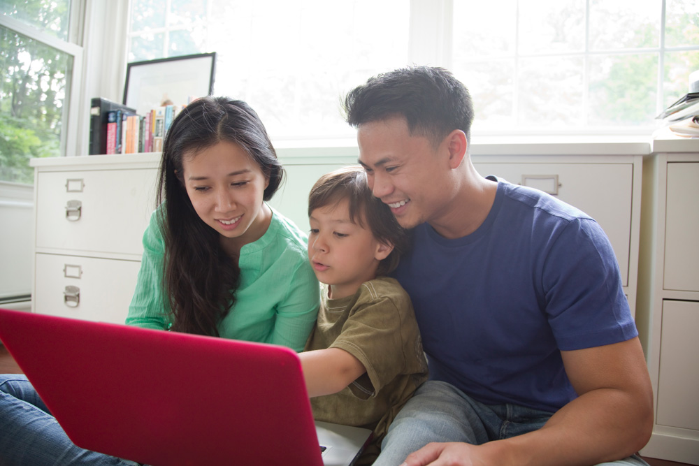 A young family of three staring at a laptop together