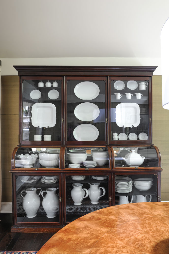 dark wood china cabinet with glass front and white dishes