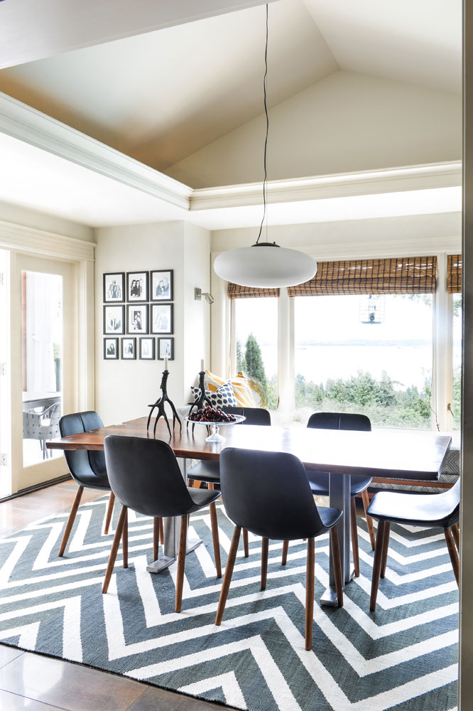 dining area with six black chairs with wooden legs and black and white chevron rug