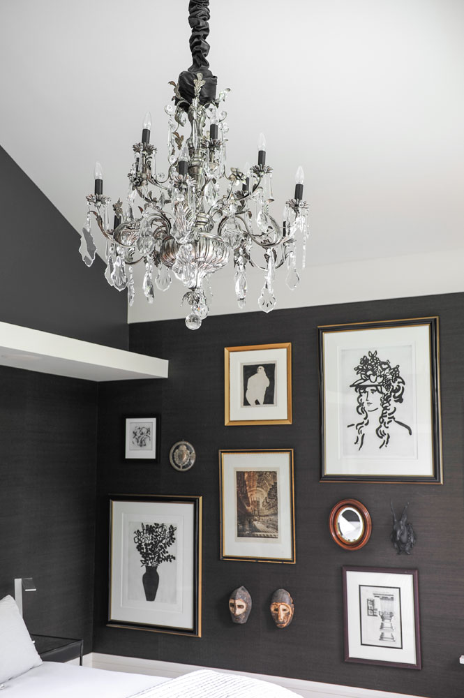 chandelier in grey wallpapered bedroom with art wall