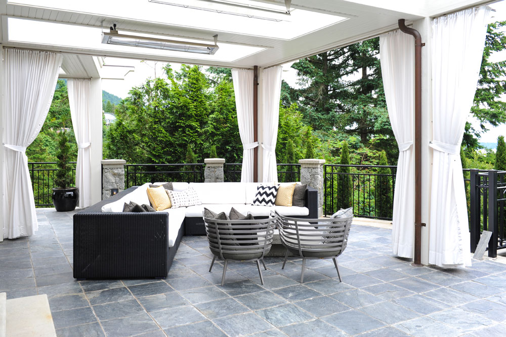 outdoor room with white curtains, sectional and two grey bucket armchairs