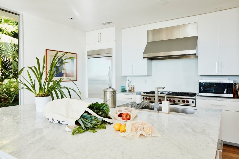 All-white kitchen with groceries on countertop.