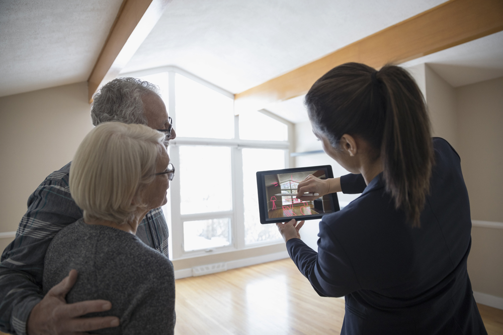 Real estate agent shows older couple design on tablet