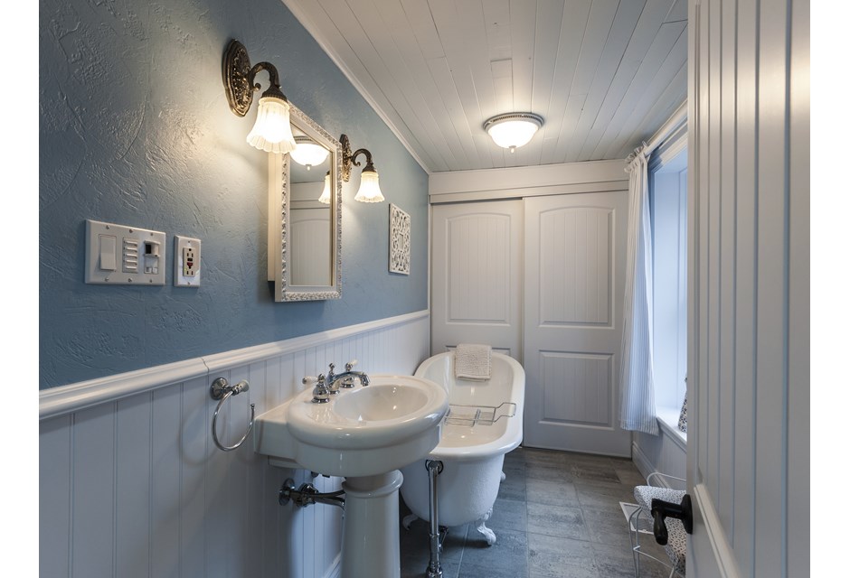 A blue and white cottage bathroom with soaker tub and bright window
