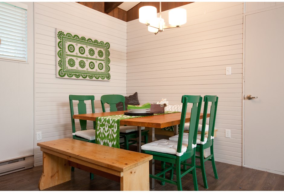 Bright green chairs and artwork in a kitchen area mostly in natural wood and basic whites