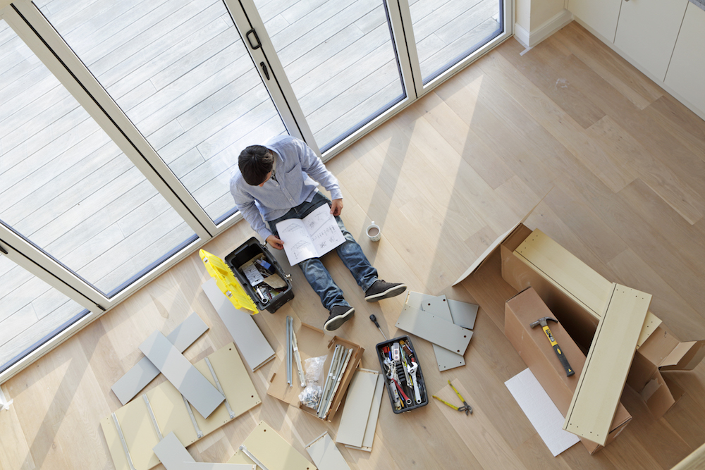 Man sat on floor surrounded by flat pack furniture