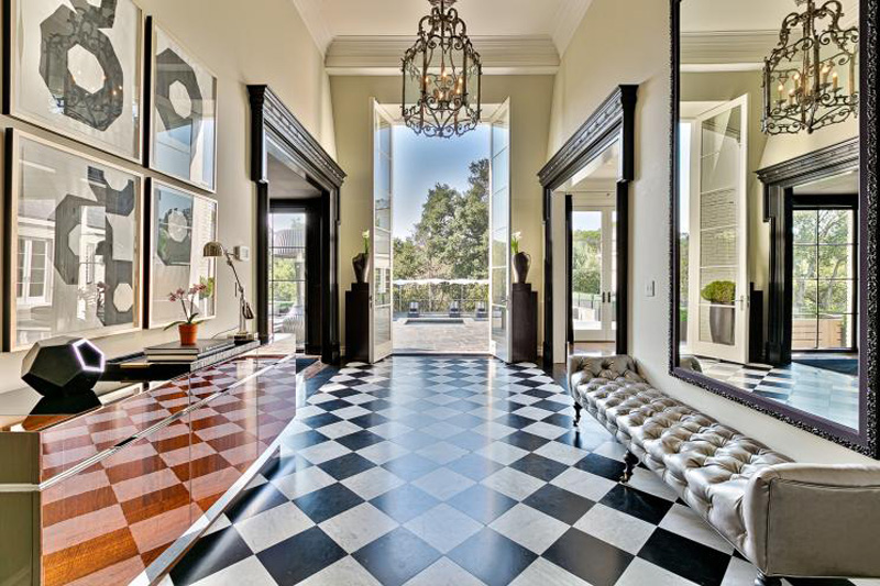 The front entryway of the Bellagio Grand with a black-and-white checkered floor, chandelier and chaise lounge