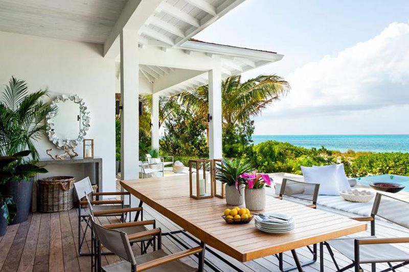 A wood dining table on a patio overlooking the Caribbean