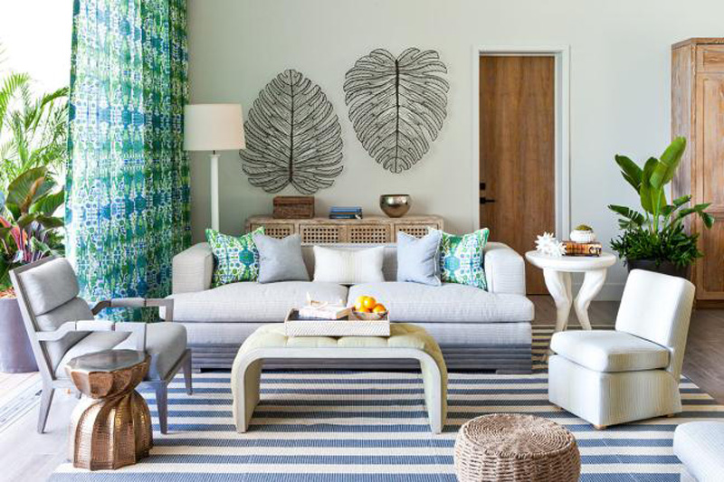 Beachy decor in a living room with striped rug, wicker furniture and curtains for maximum shade
