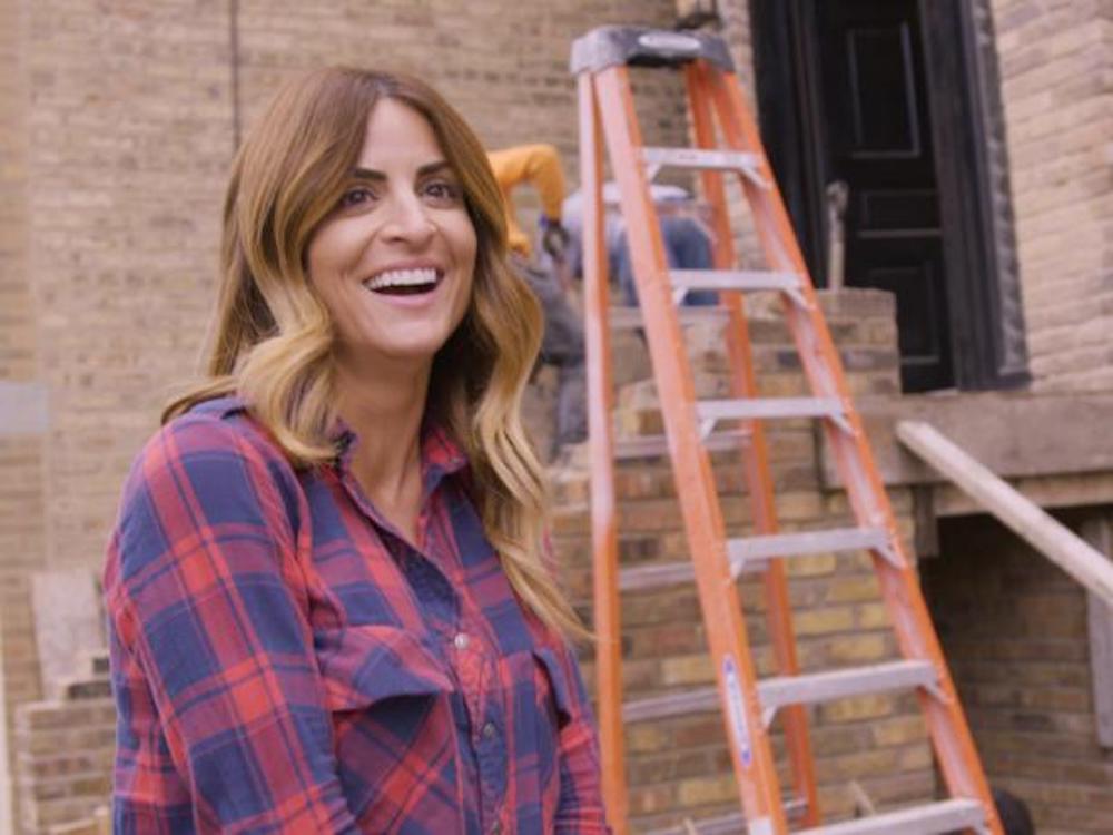 Alison Victoria drills a hole in the wall on Windy City Rehab a renovation show on HGTV