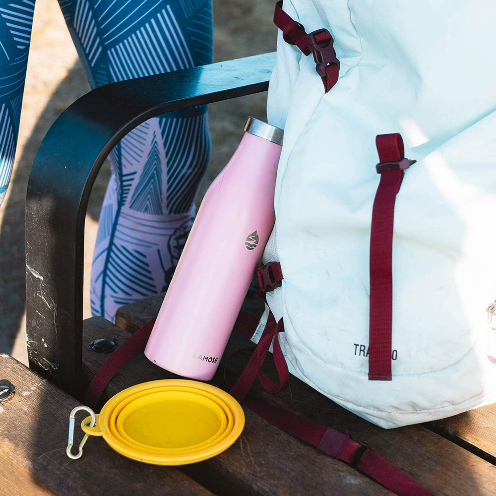 White hiking backpack next to pink insulated water bottle