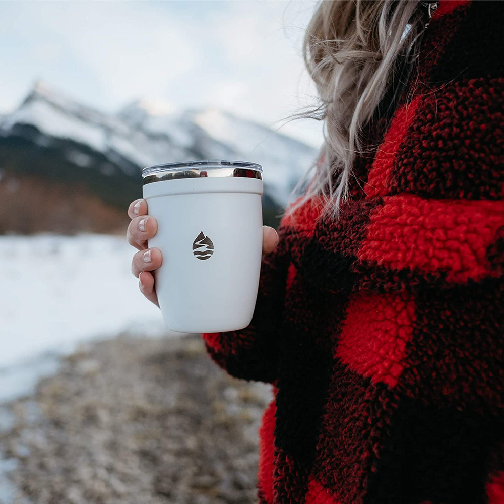 Woman in red plaid jacket holding a white insulated wine tumbler