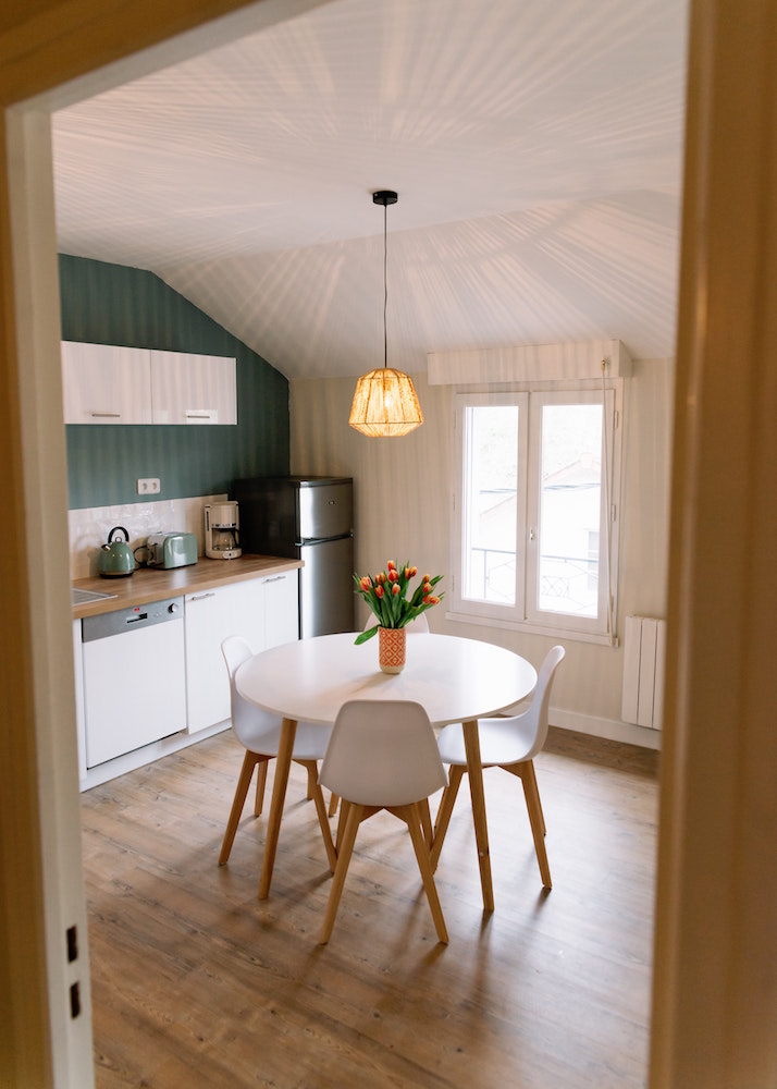 small kitchen with white round table and green feature wall