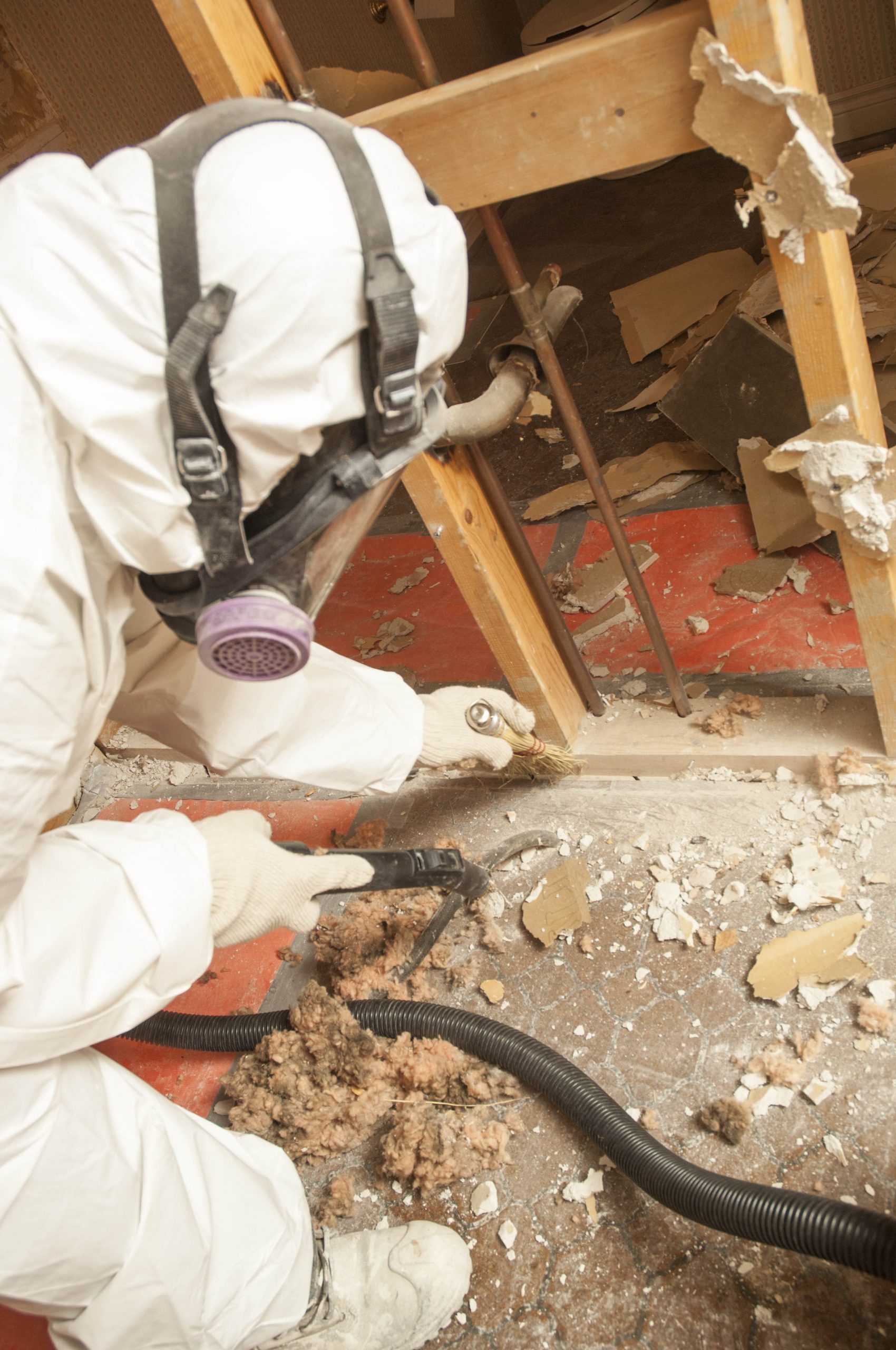 A man in a white hazard mat suit cleaning asbestos