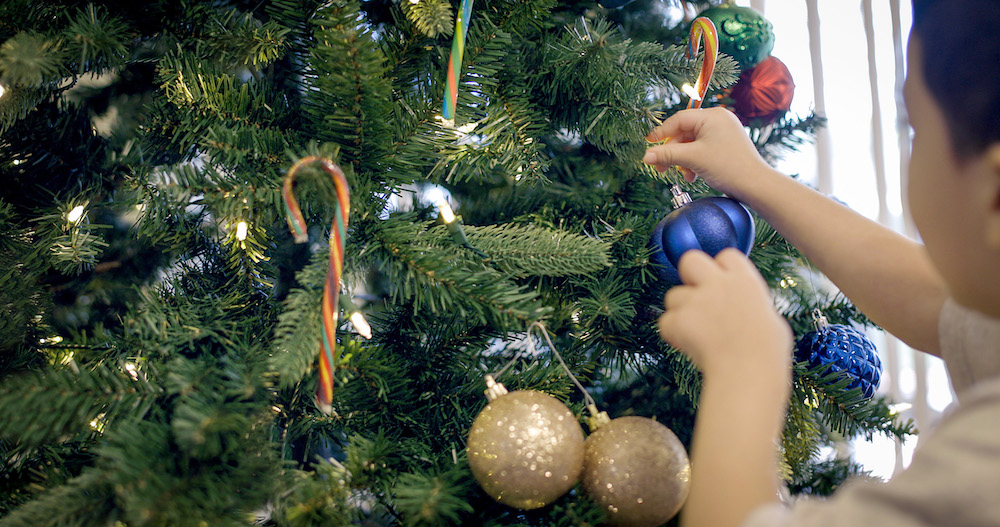 boy hanging decoration on Christmas tree with candy canes