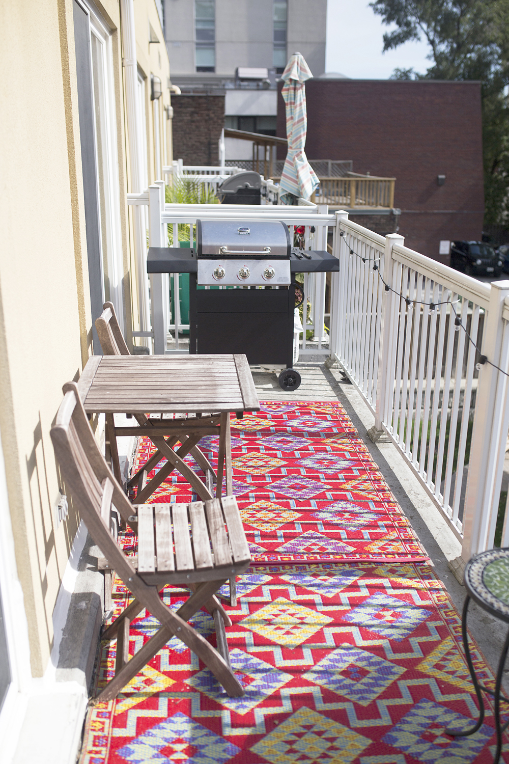 A long, narrow condo balcony with an outdoor area rug
