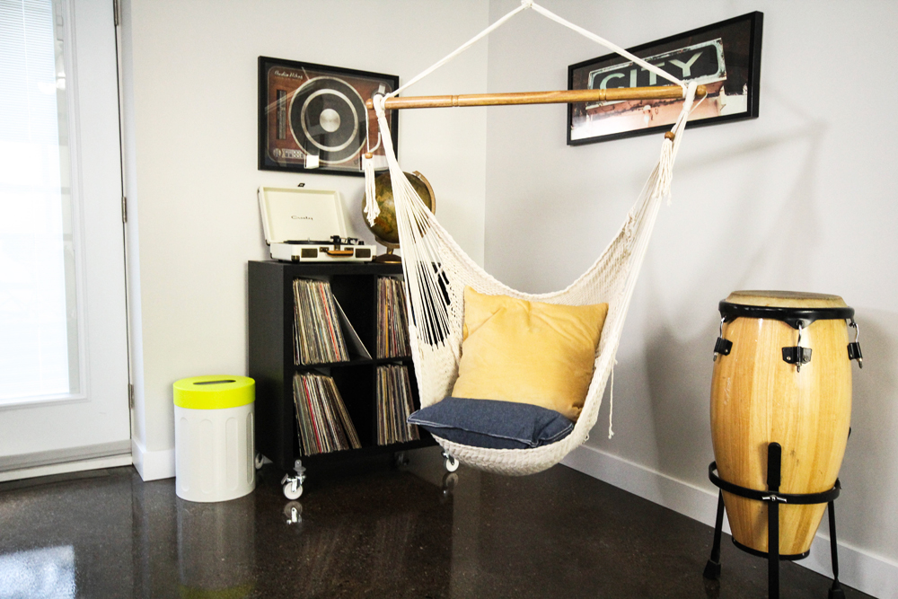 A hammock hanging in the middle of a music room in a monochromatic space