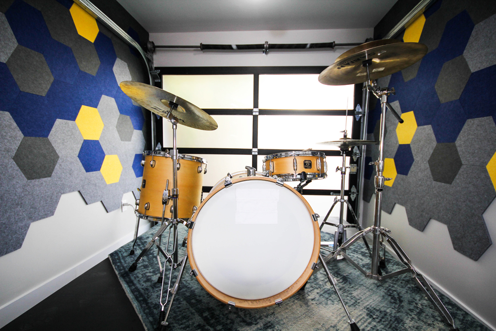 A drum kit in a living room nook with accent walls made of coloured soundproofing boards