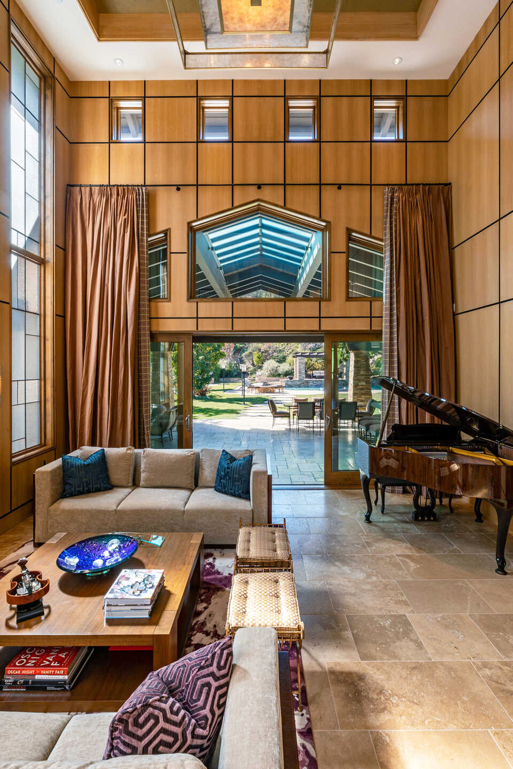 A living room space with sky-high ceilings and a majestic grand piano in the corner