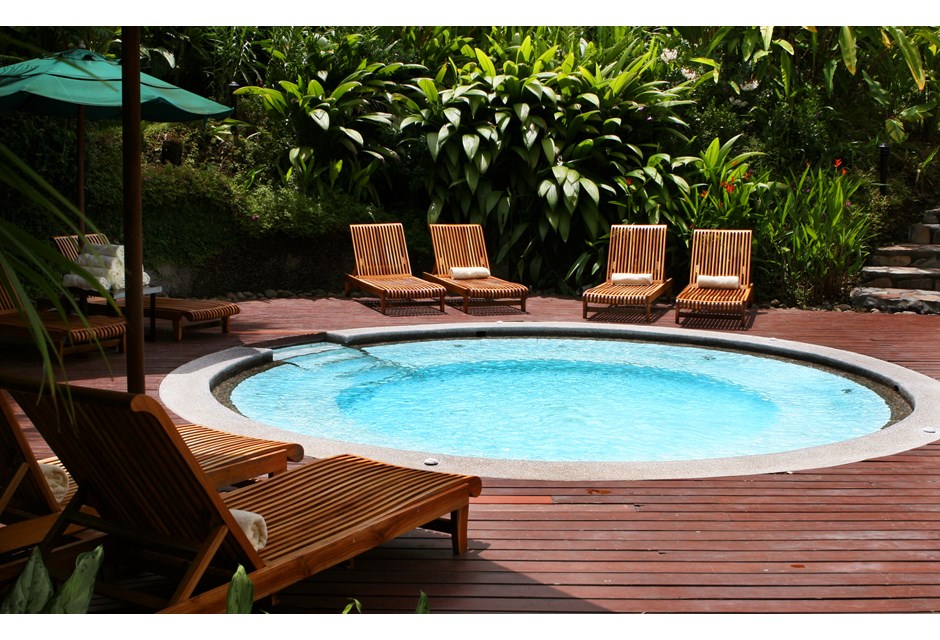 A unique circular backyard pool surrounded by patio furniture