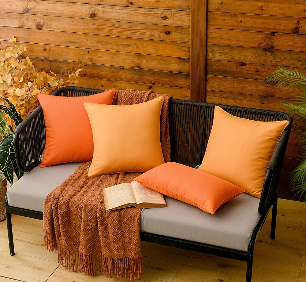 assorted orange pillows on black bench