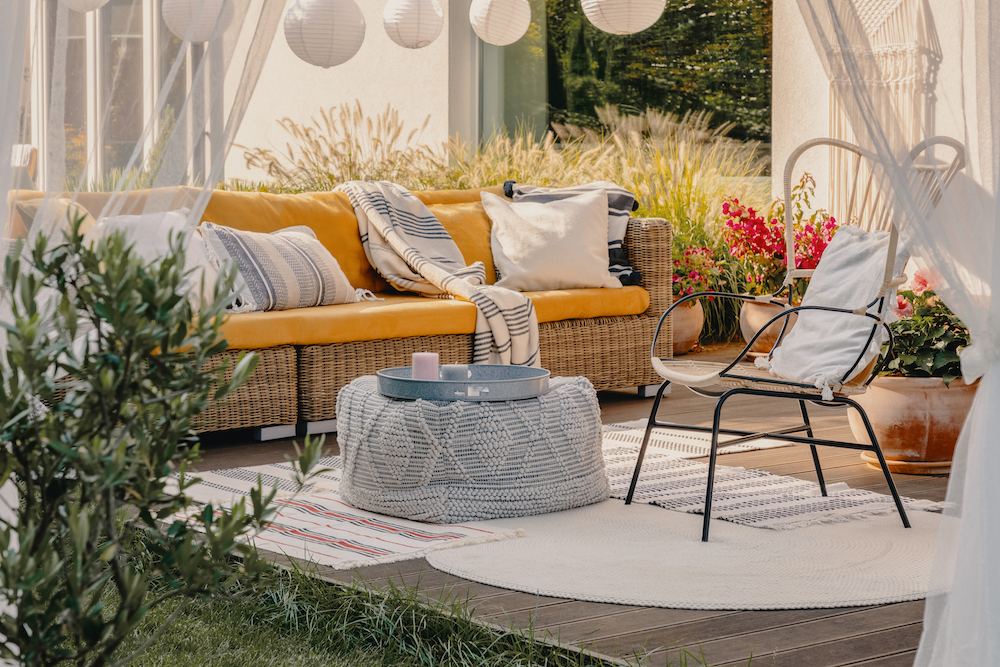outdoor armchair, pouf as a table, wicker couch and rugs on terrace