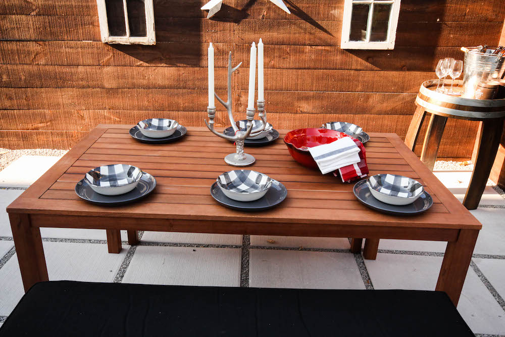 wood outdoor dining table set with plaid dishes and candelabra