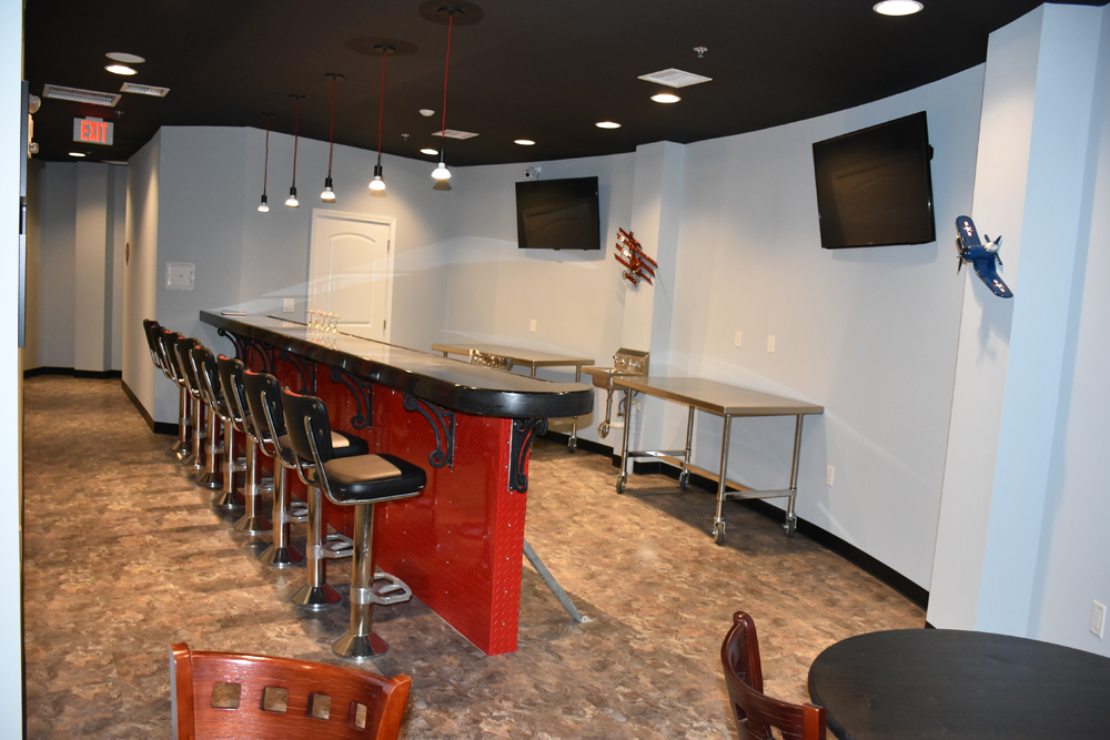 A bar lounge space with bartop chairs and TVs in a condo bunker