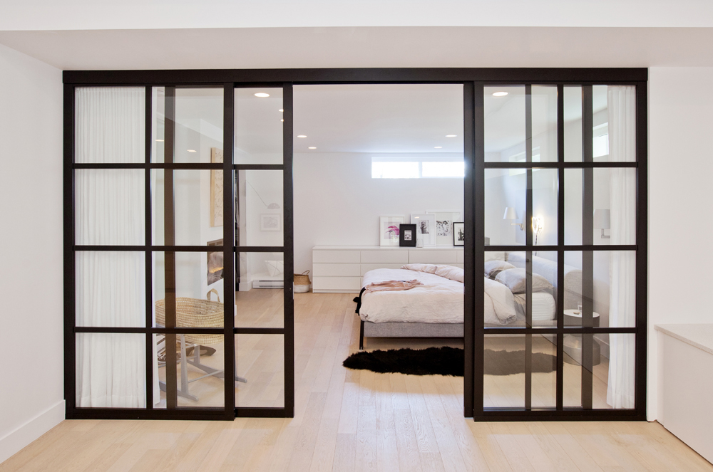 Floor-to-ceiling sliding French doors that separate a basement bedroom from the living quarters