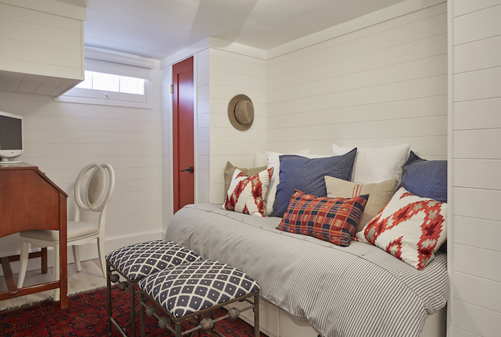 White shiplap bedroom with a desk, bed, and red and blue decor accents