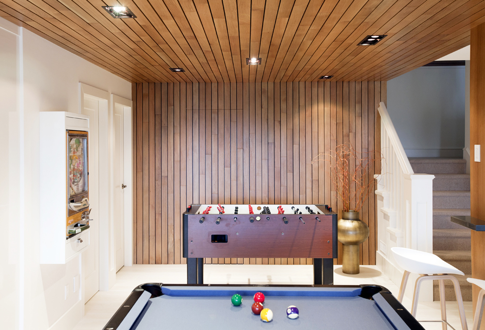 A white oak wall and ceiling in a mostly white basement games room