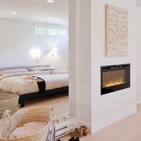 An open-concept basement apartment featuring a built-in fireplace and bright white walls