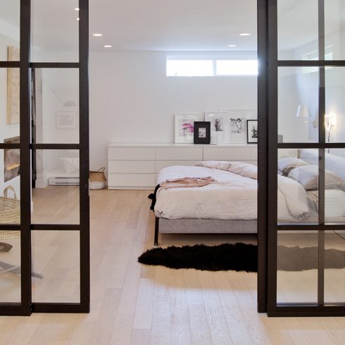 Glass doors separate the bedroom from the living area in a basement apartment