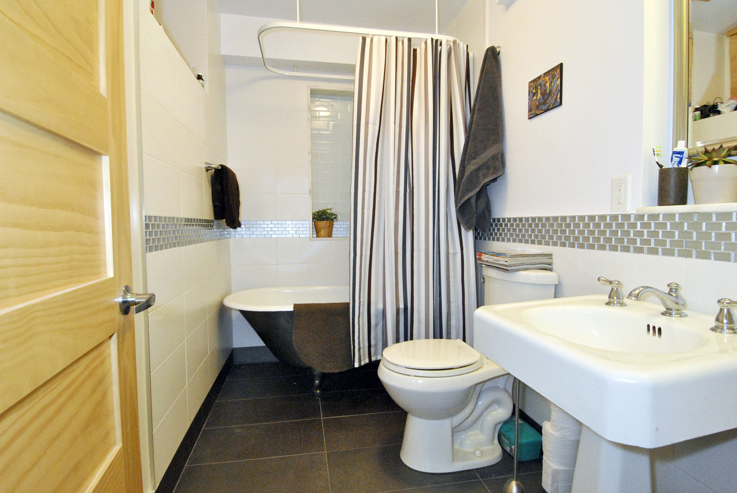Basement apartment bathroom with claw-foot bathtub and sink area