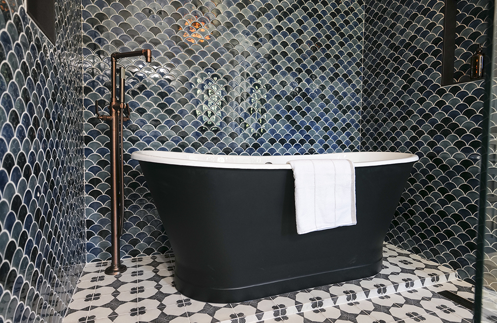 Black soaker tub in small tiled bathroom