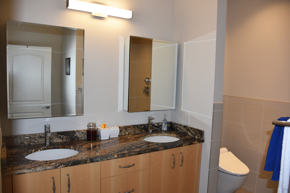 A bathroom space with a double vanity and toilet off to the side