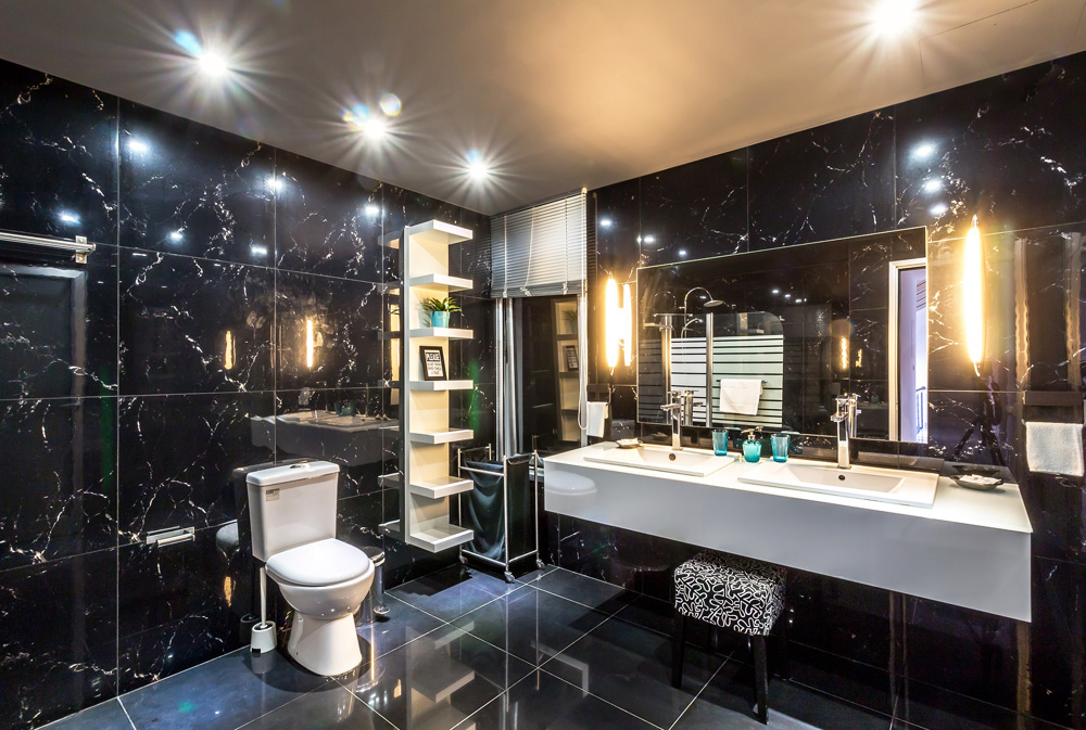 Black marbled tiles on the walls and floor of this spacious bathroom renovation
