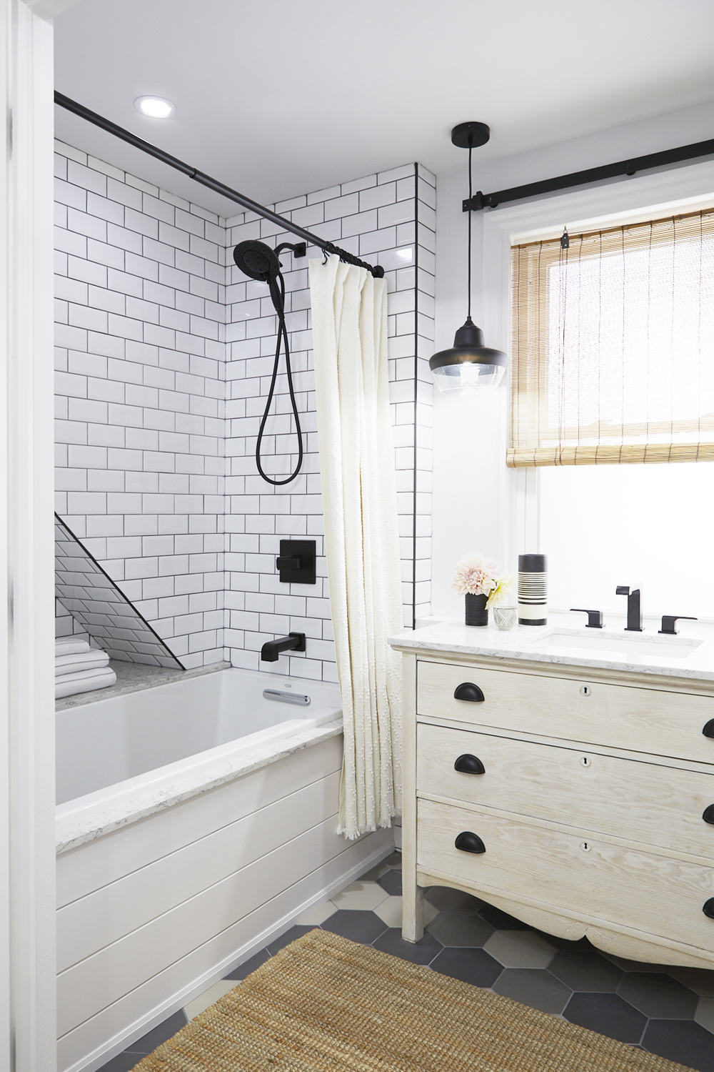 A classic subway tile in the shower of a renovated monochromatic bathroom