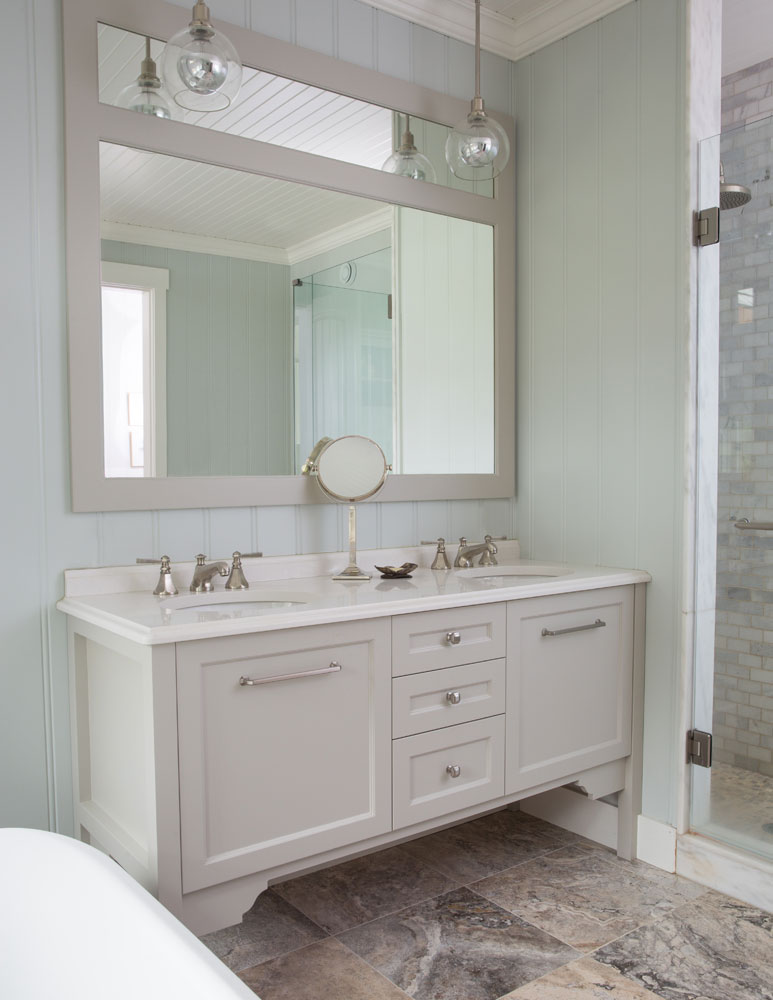 beige two-sink vanity with beige two section mirror and two clear pendants above