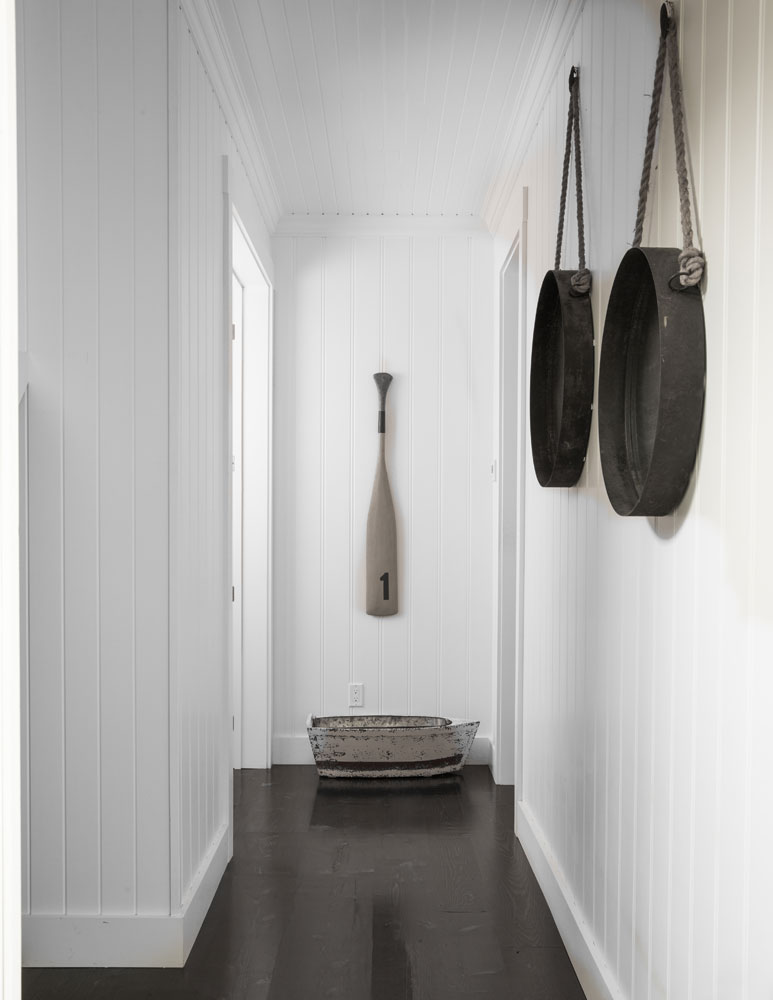 white hallway with two wall hangings and oar hung at end