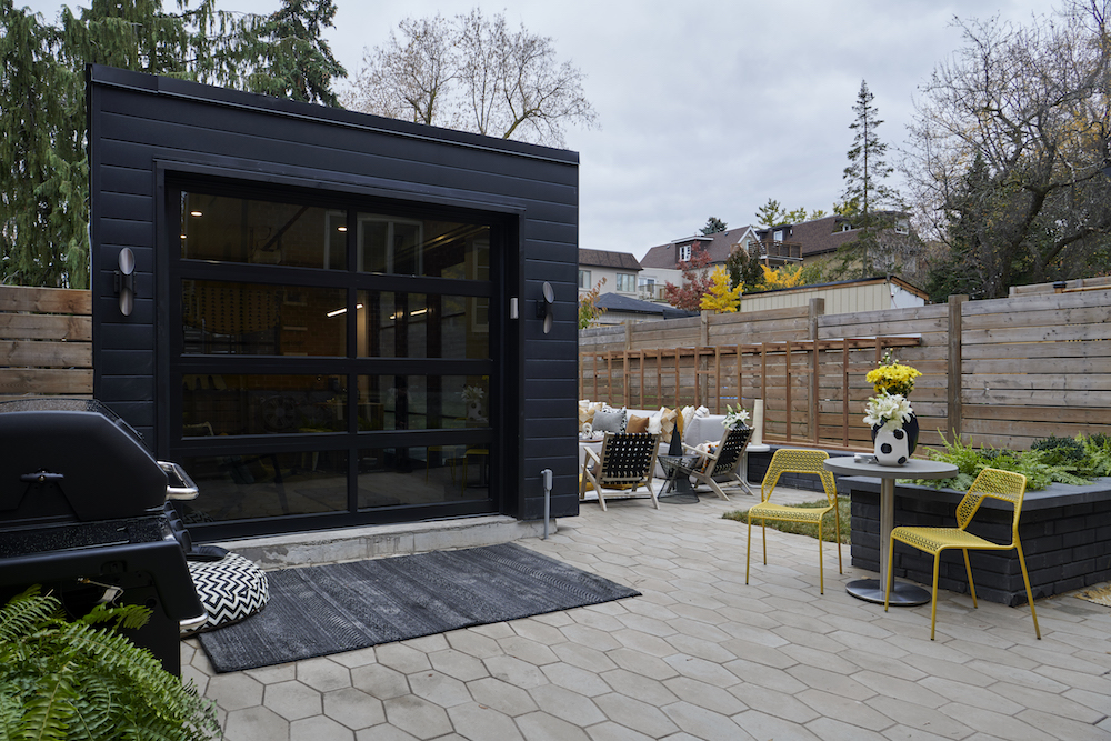 A backyard with renovated shed for lounging, hex stone walkway and a brand new barbecue setup