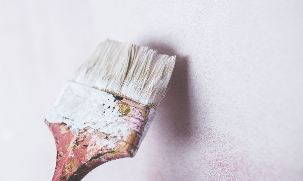 A paintbrush against a white wall.