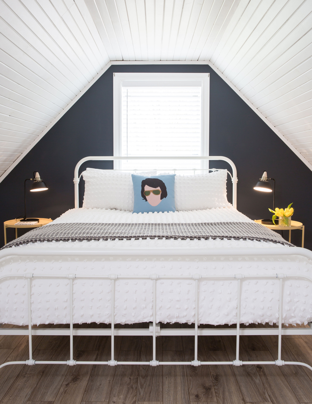 A renovated attic with a dark navy blue accent wall and Elvis-inspired throw pillows