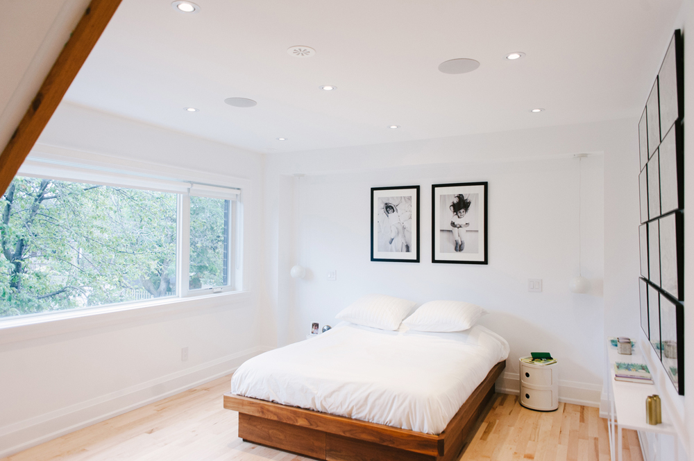 A minimalist bedroom with a low-to-the-ground bed with art hanging on the wall above