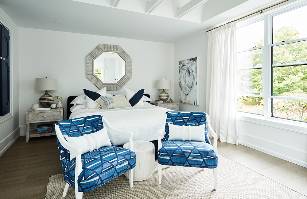 A white and indigo bedroom with area rug and large above-bed mirror