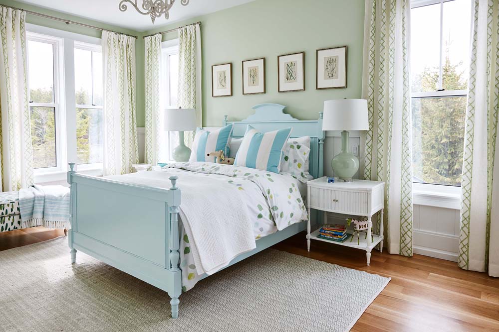 A pale mint green bedroom with a matching pastel blue bed and white pillows