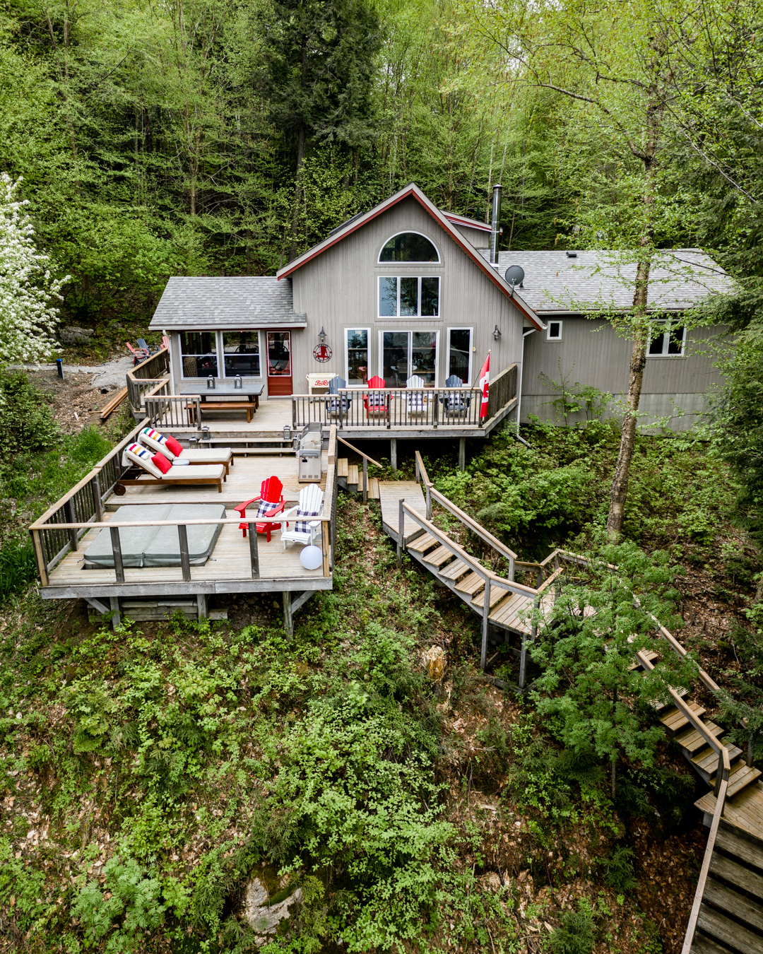 Exterior cottage shot, three decks, staircase, muskoka chairs, Bay blankets on loungers